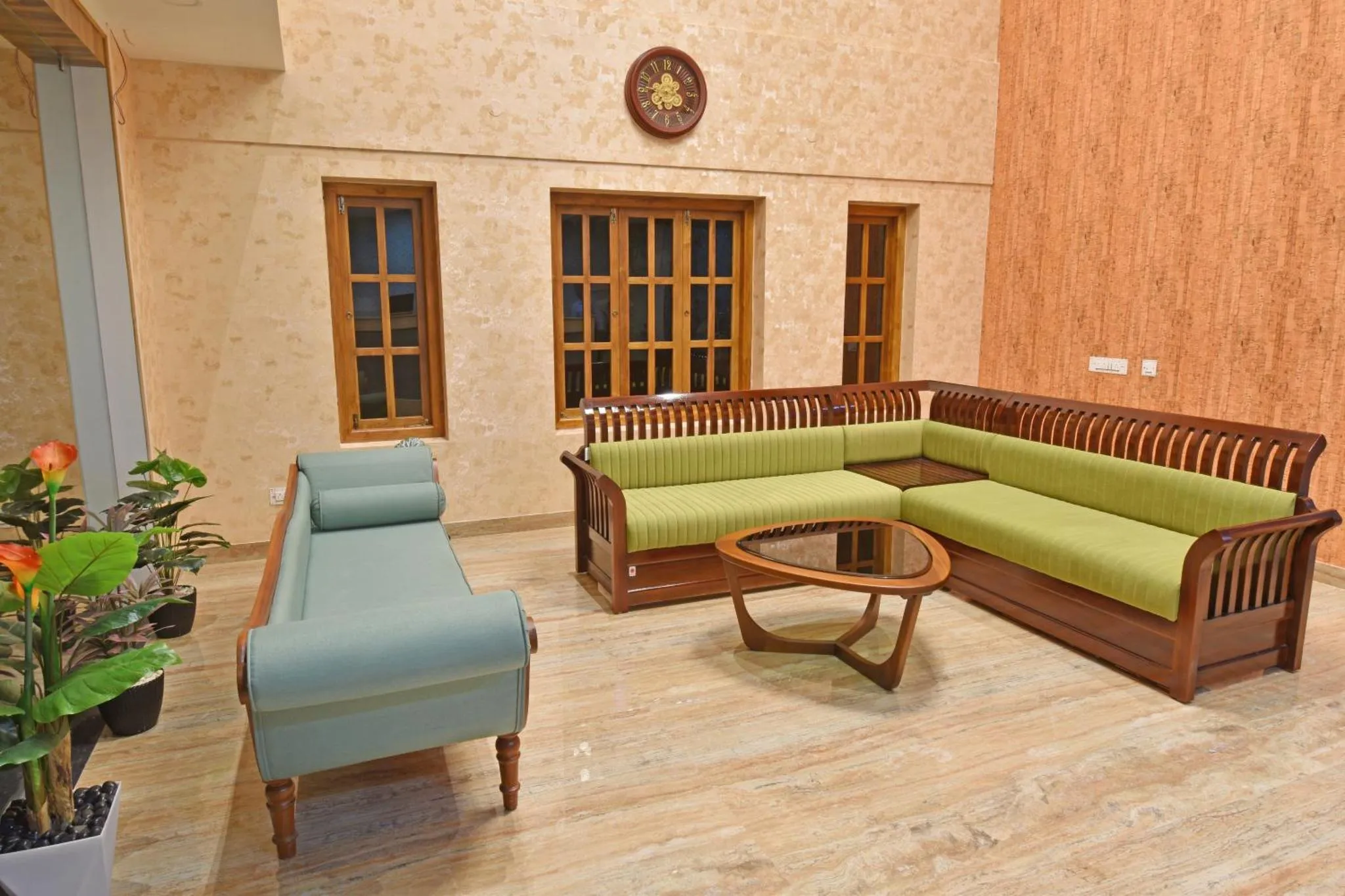 Un espace de détente intérieur avec un canapé d'angle en bois et des coussins verts.