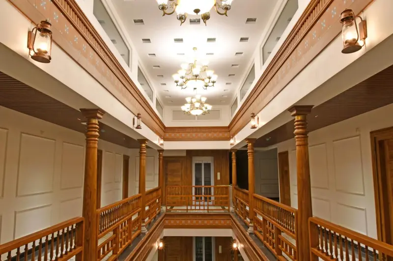 Un long couloir intérieur avec des colonnes en bois et des lustres.