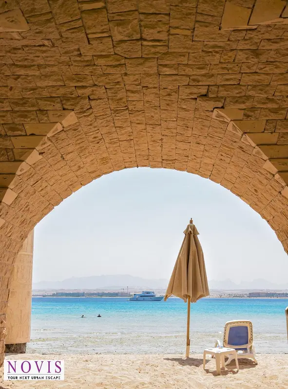 Une arche en pierre donne sur une plage de sable fin et une mer turquoise.