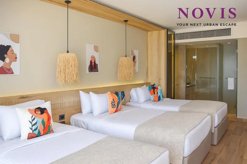 Une chambre d'hôtel avec deux lits jumeaux et des coussins colorés.