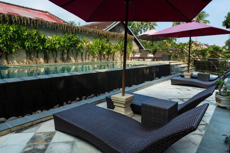 Transats et parasols bordent une piscine rectangulaire.