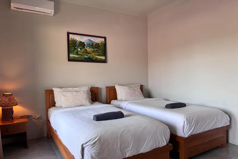Une chambre lumineuse avec deux lits simples et une décoration murale.