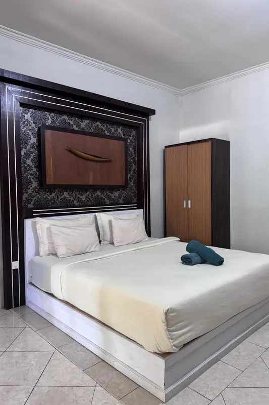 Une chambre avec un grand lit et une décoration murale sombre.