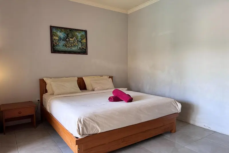 Une chambre lumineuse avec un grand lit recouvert d'une courtepointe blanche et de serviettes roses.