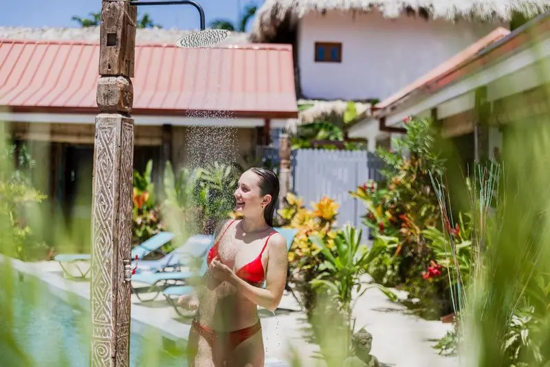 Une femme se douche en plein air dans un jardin tropical.