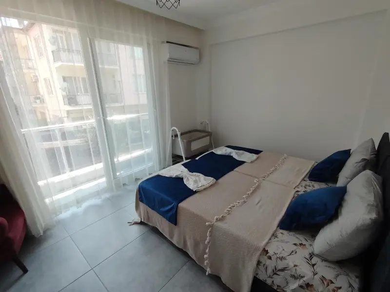 Une chambre lumineuse avec un grand lit et un accès à un balcon.