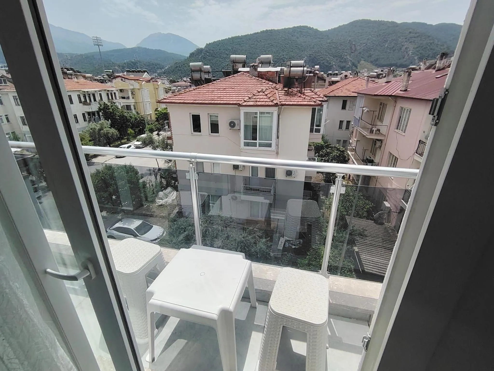 Vue d'une terrasse avec mobilier blanc donnant sur un paysage urbain et montagneux.