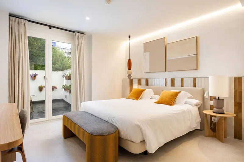 Une chambre lumineuse avec un grand lit et un accès à une terrasse.