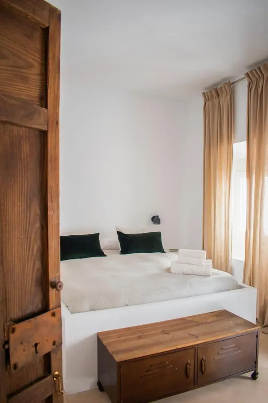 Une chambre lumineuse avec un lit fait et une commode en bois.