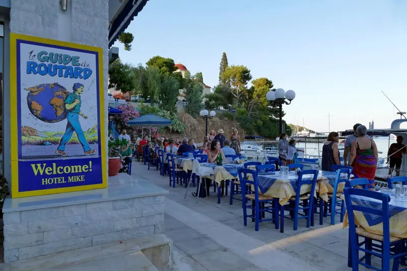 Une terrasse de restaurant avec des tables bleues et des clients attablés.