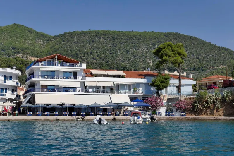 Bâtiment blanc avec des balcons surplombant une plage ensoleillée.