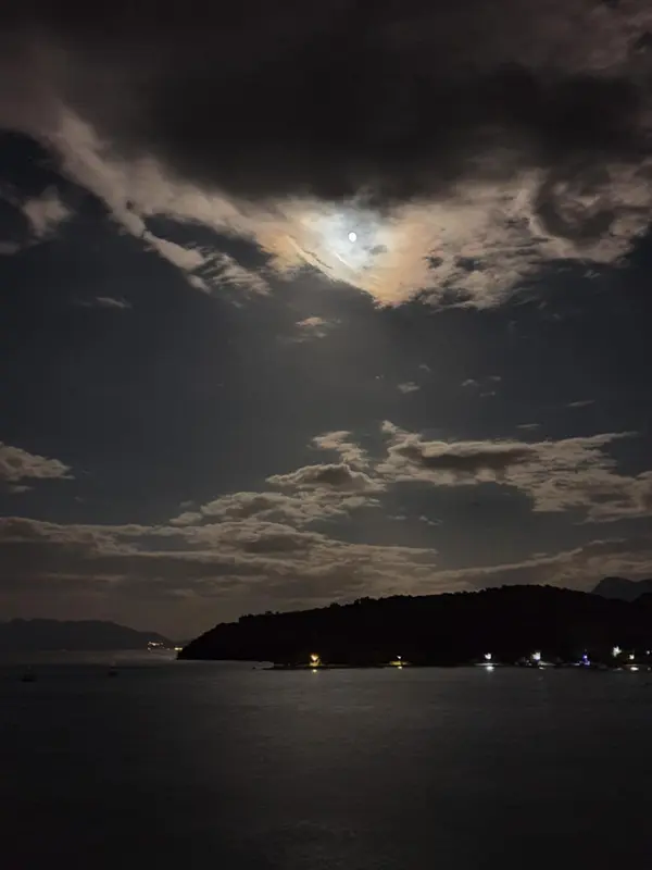 Ciel nocturne nuageux au-dessus d'une côte sombre et illuminée.