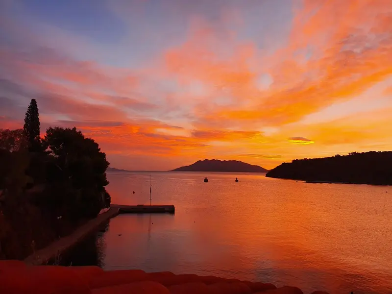 Coucher de soleil sur la mer avec des montagnes en arrière-plan.