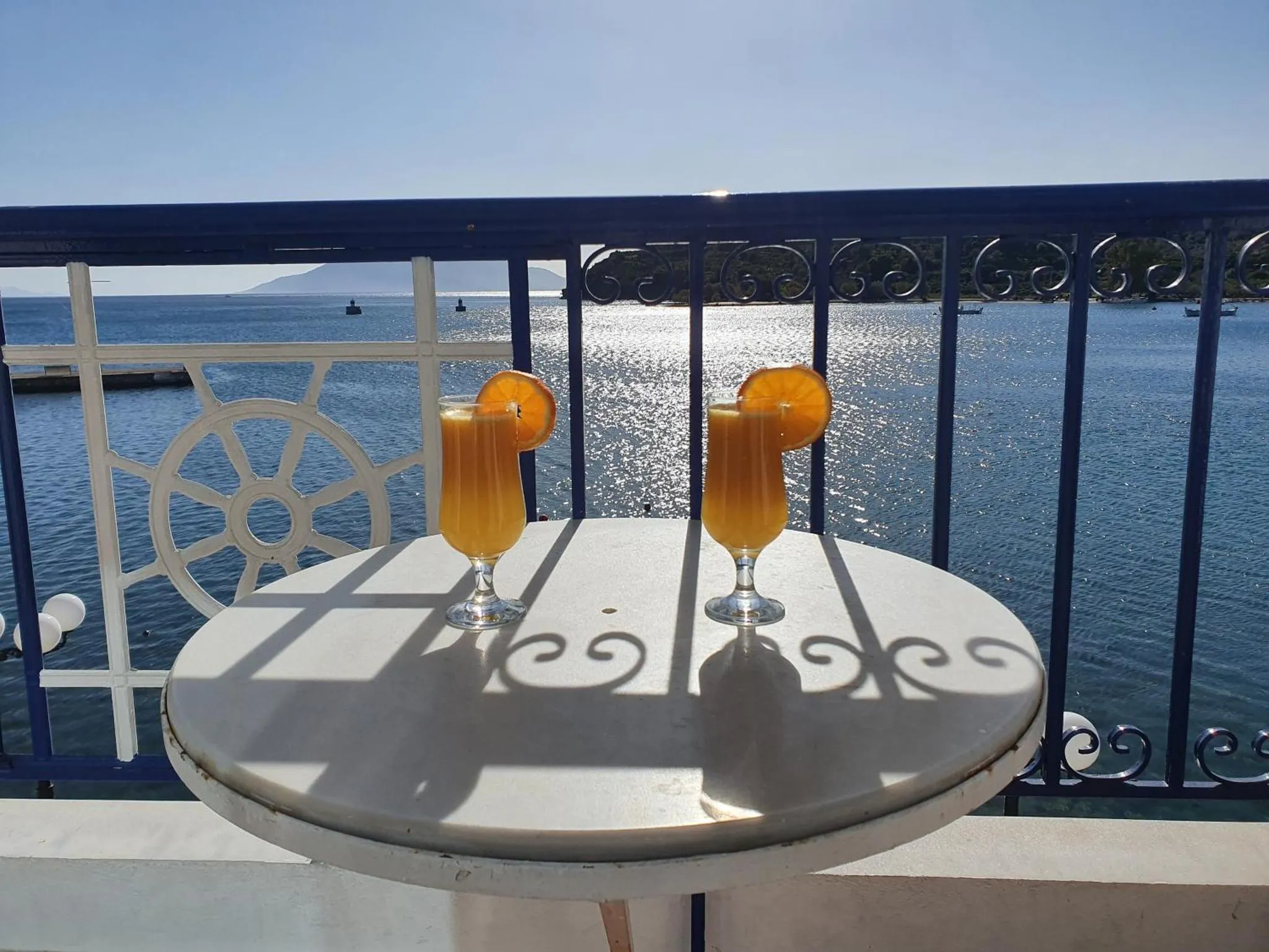 Une table ronde avec deux verres sur une terrasse ensoleillée avec vue sur la mer.