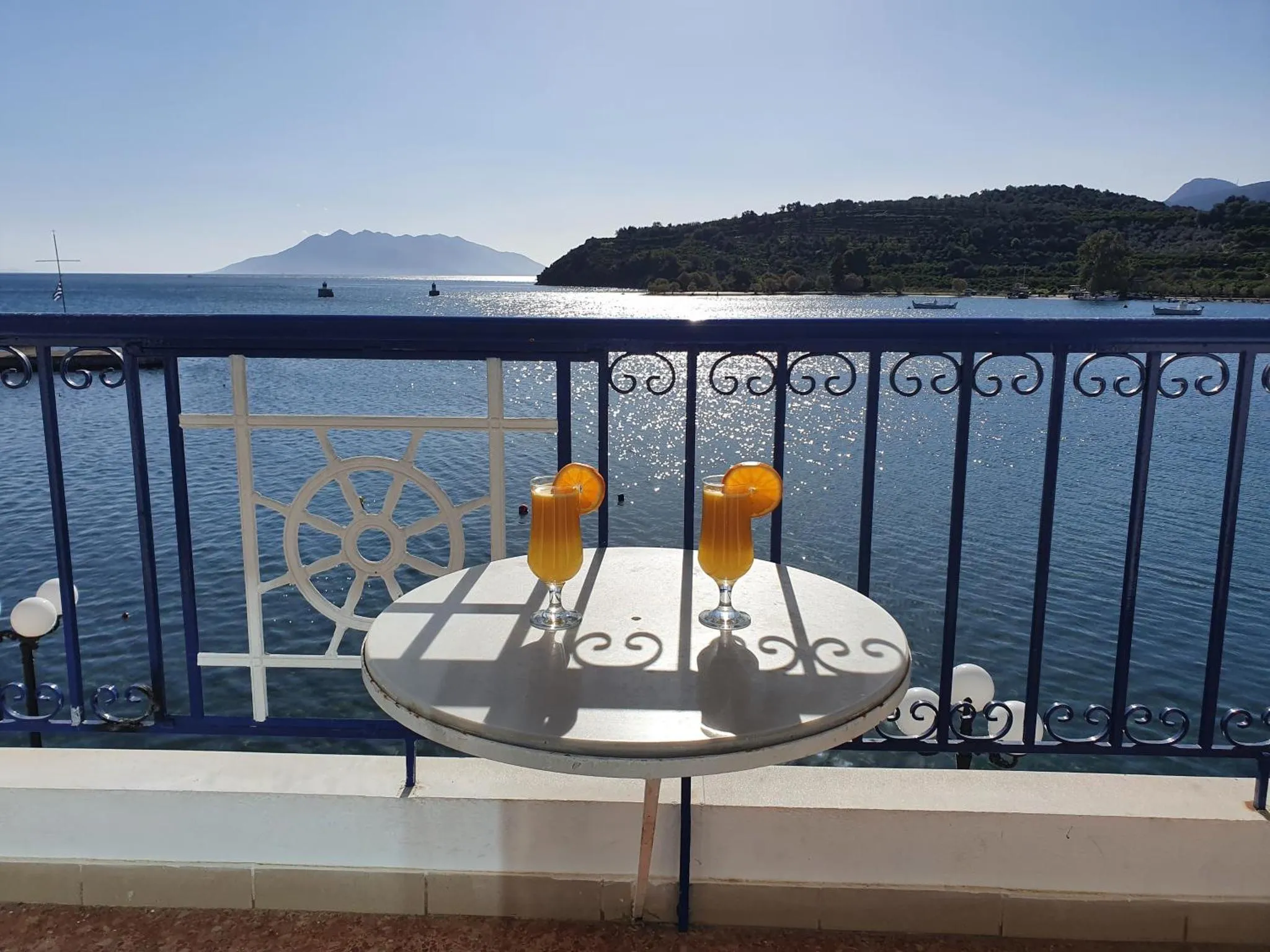 Une table avec des verres sur une terrasse ensoleillée avec vue sur la mer.