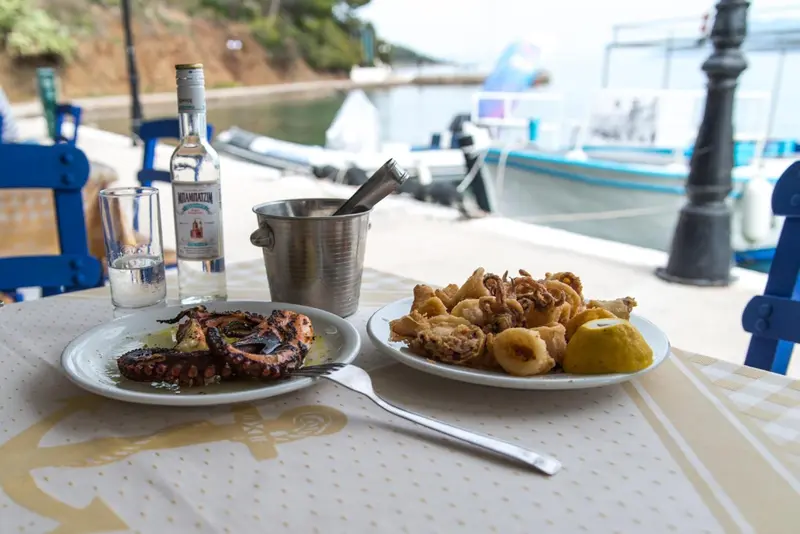 Une table est dressée avec des plats de fruits de mer et une bouteille.