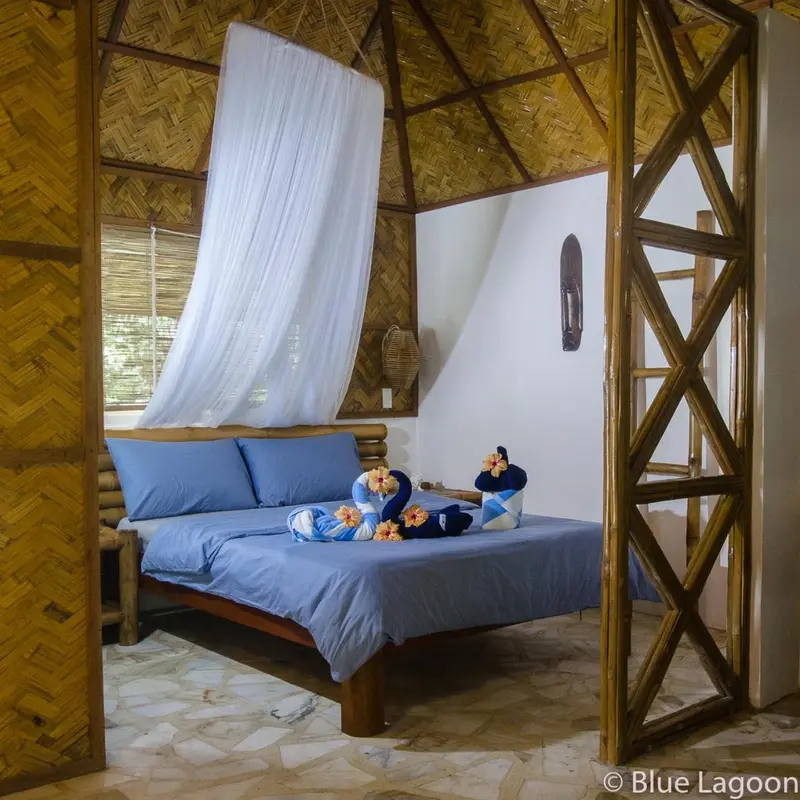 Une chambre avec un lit recouvert de moustiquaire et décoré de fleurs.