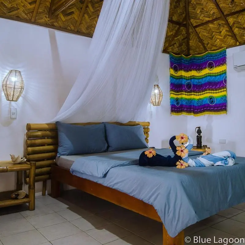 Une chambre lumineuse avec un lit recouvert d'une moustiquaire et décoré de fleurs.