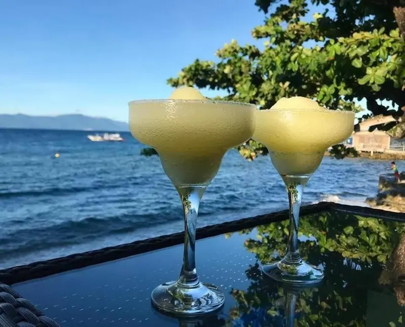 Deux cocktails exotiques sont servis sur une table face à la mer.