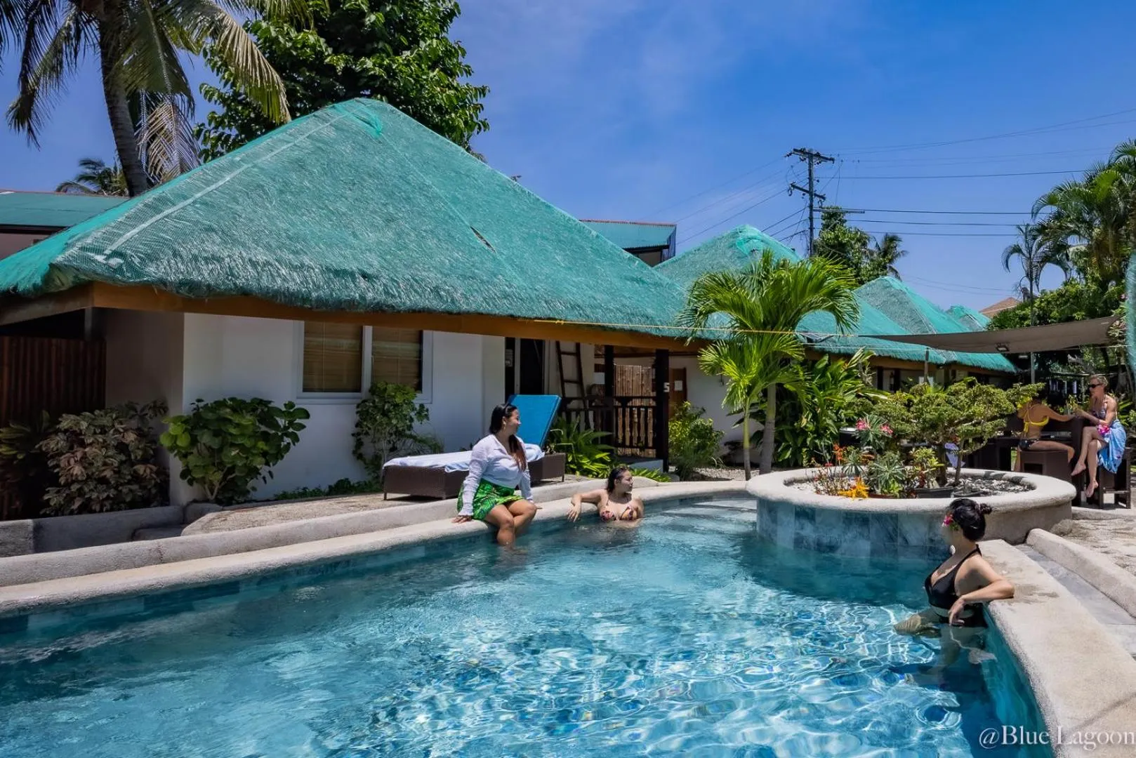 Des personnes se détendent au bord d'une piscine dans un cadre tropical.
