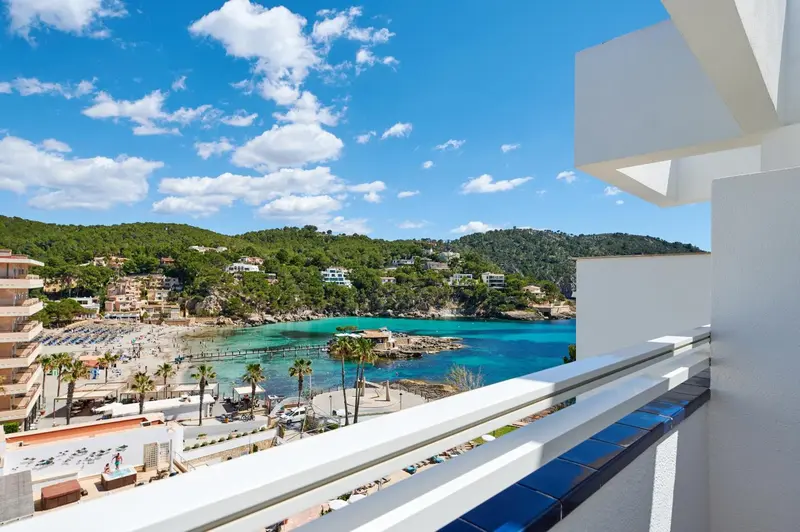 Vue d'une crique ensoleillée depuis un balcon moderne.