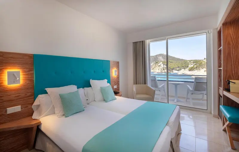 Chambre lumineuse avec un grand lit et une vue sur la mer.