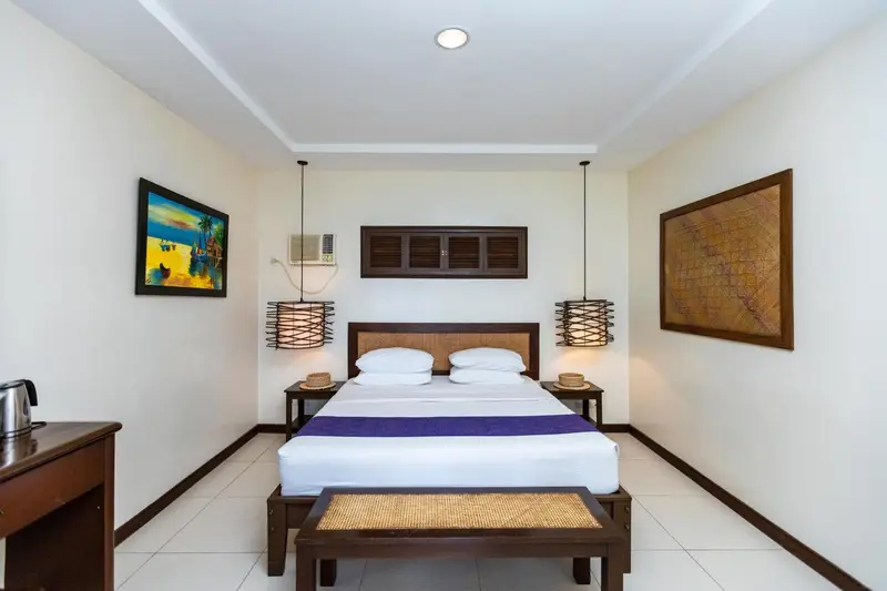 Une chambre lumineuse avec un grand lit et des tableaux décoratifs.
