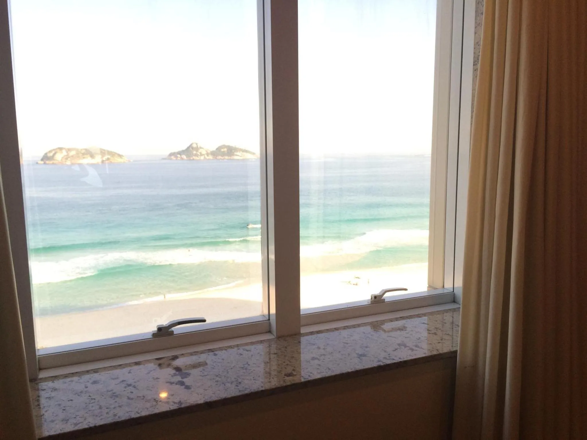Vue sur la mer depuis une fenêtre de chambre.
