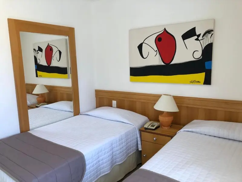 Une chambre lumineuse avec deux lits simples et une décoration murale colorée.