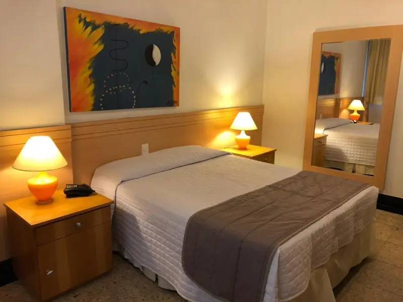 Une chambre lumineuse avec un grand lit et des lampes de chevet.