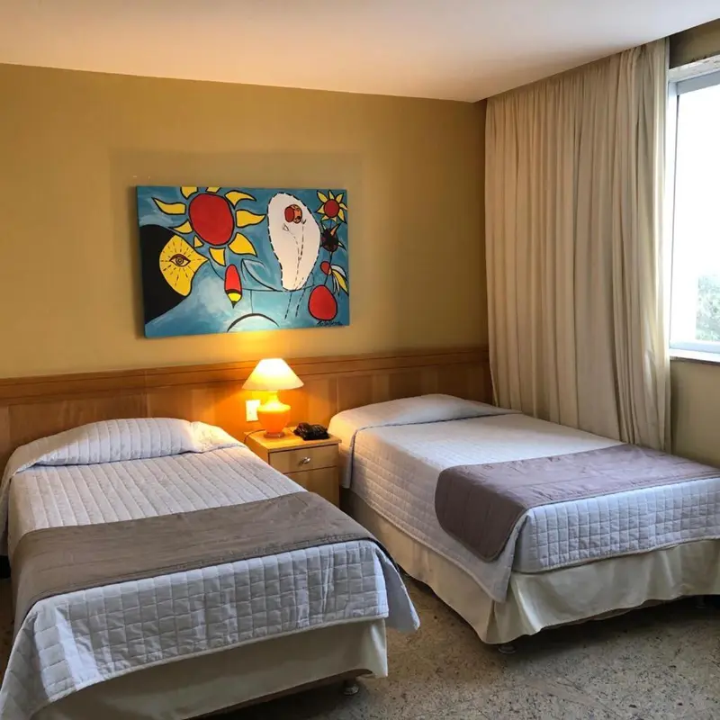Une chambre d'hôtel avec deux lits simples et une décoration murale colorée.
