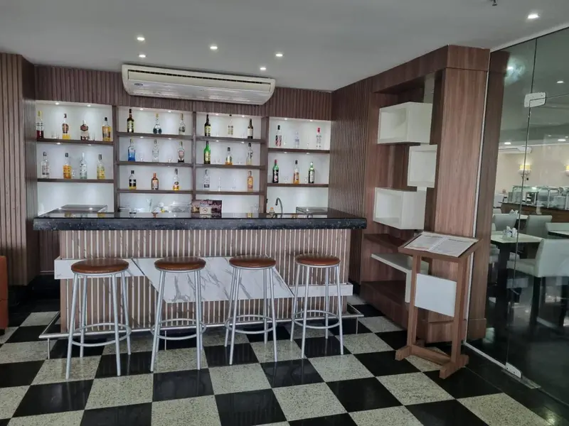 Un comptoir de bar avec des tabourets et des bouteilles exposées.