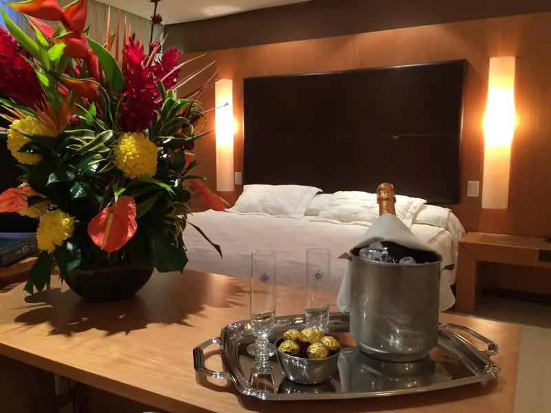 Une chambre d'hôtel avec un grand lit et une table basse décorée de fleurs et de chocolats.