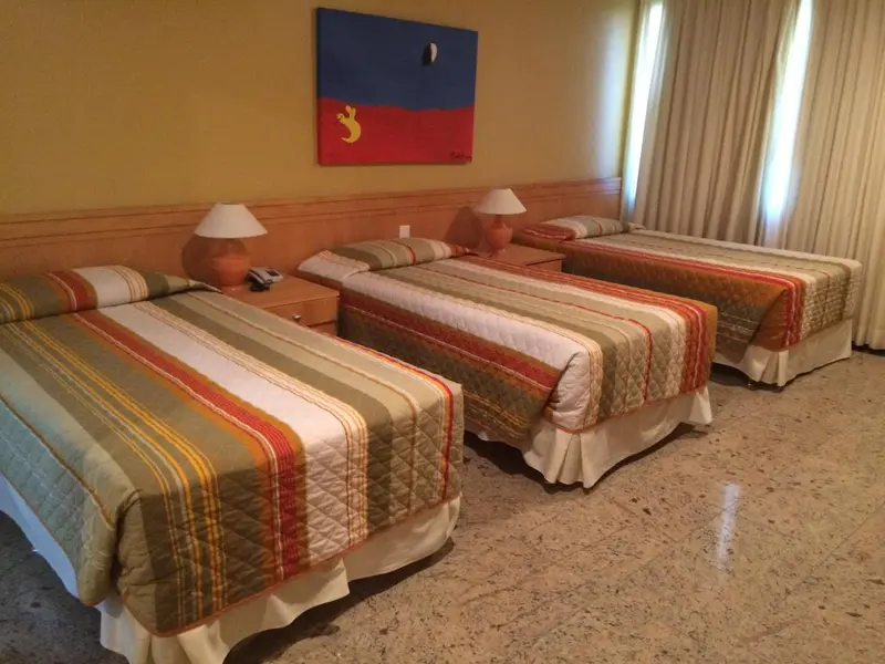 Chambre avec trois lits simples et une décoration murale abstraite.