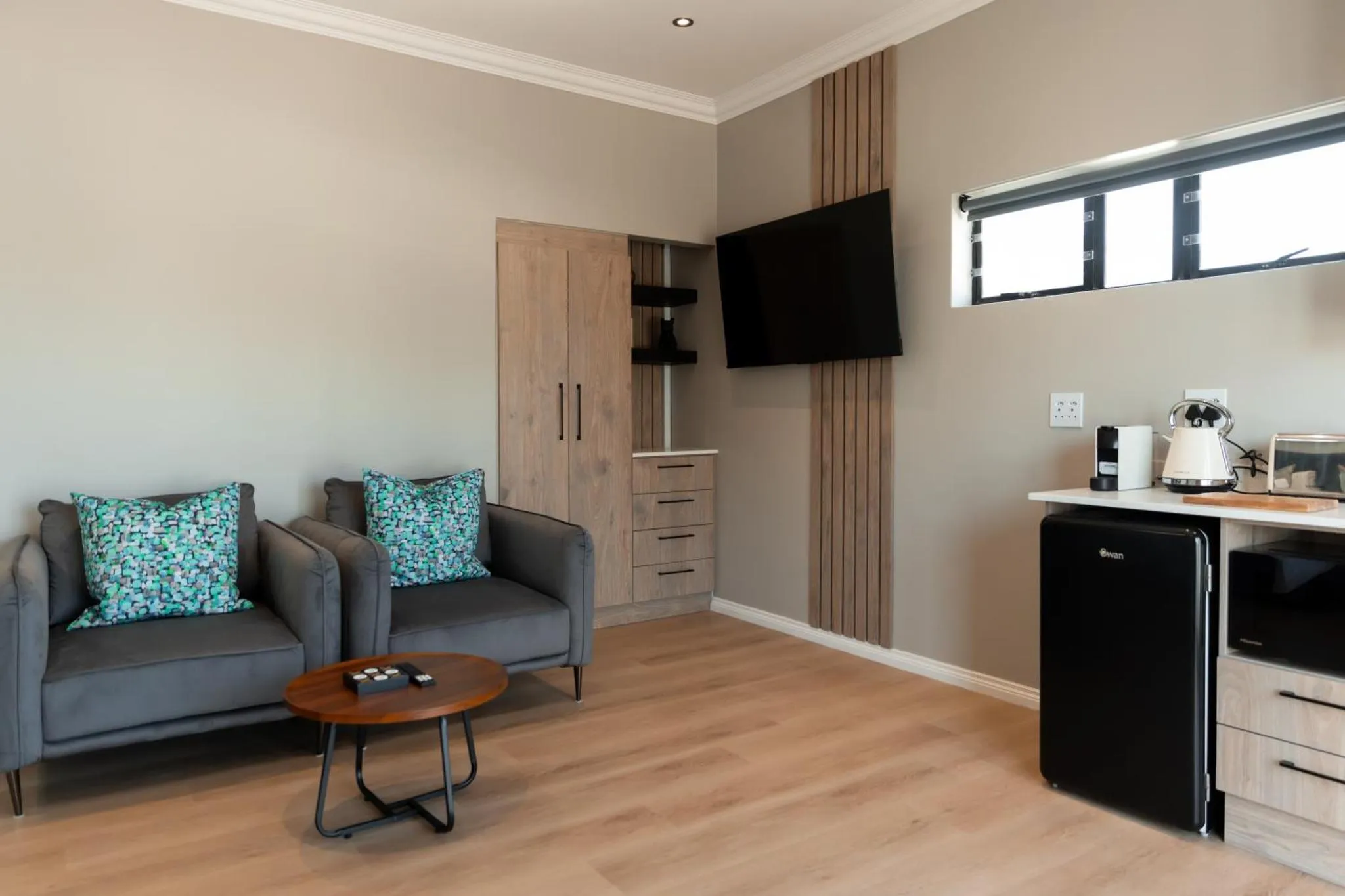 Un salon avec deux fauteuils et une kitchenette.