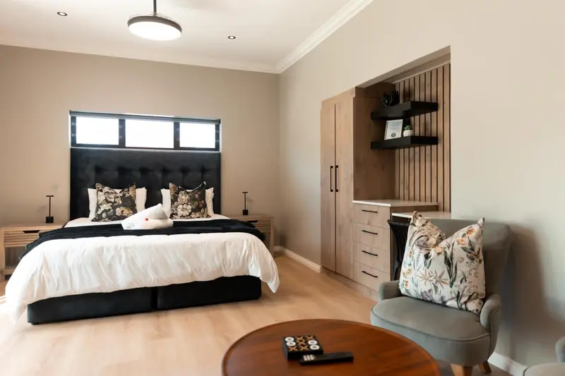 Une chambre lumineuse avec un grand lit et un fauteuil.