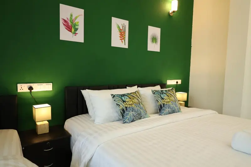 Une chambre avec un grand lit recouvert d'une courtepointe blanche et de coussins.