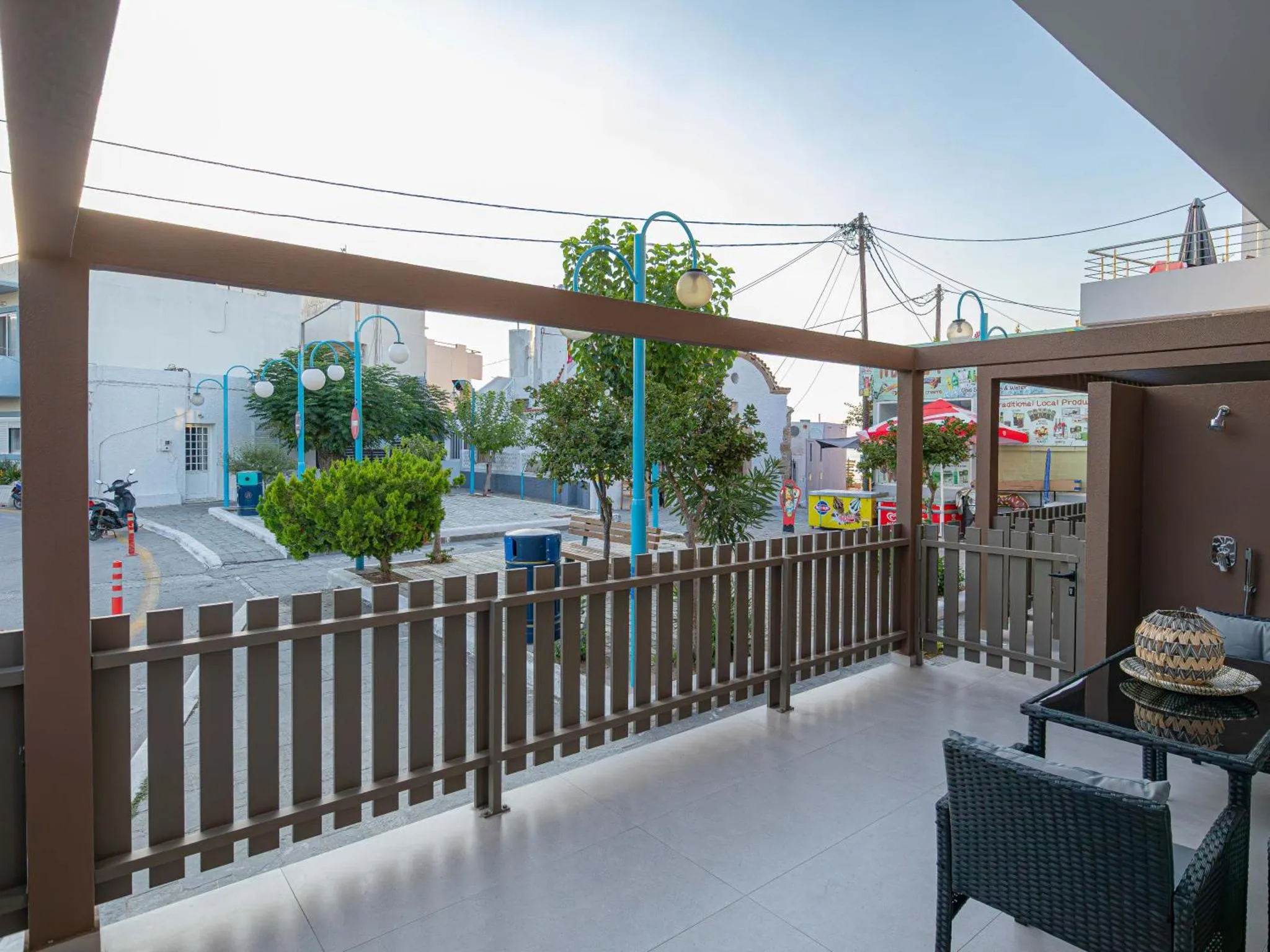 Terrasse ombragée avec mobilier de jardin donnant sur une rue.