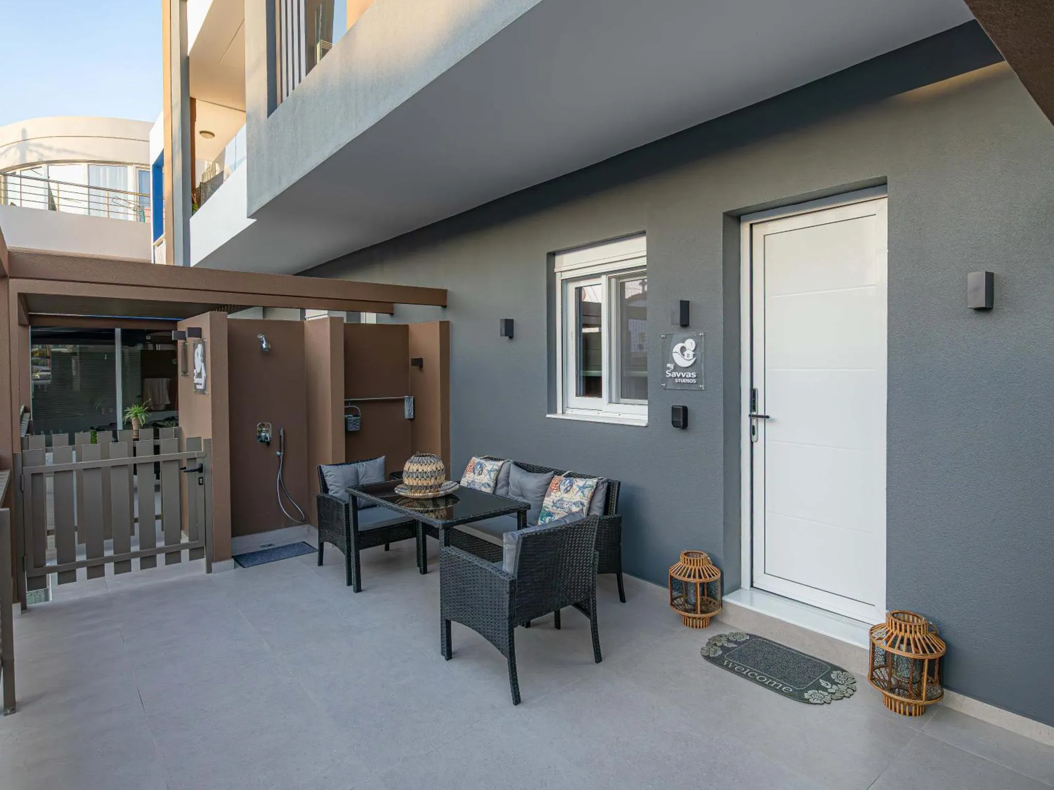Terrasse aménagée avec salon de jardin et porte d'entrée.