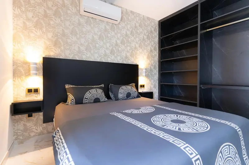 Un lit est fait dans une chambre décorée de motifs géométriques.
