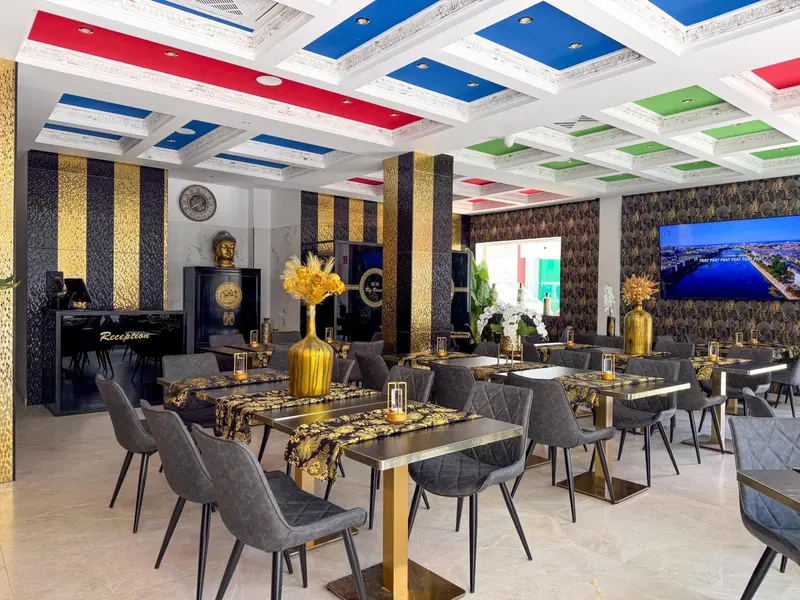Une salle lumineuse avec des tables et des chaises disposées devant un comptoir d'accueil.