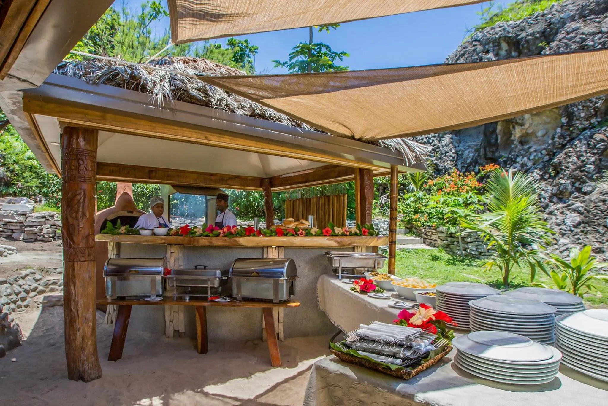 Un buffet garni est présenté sous une structure ombragée en plein air.