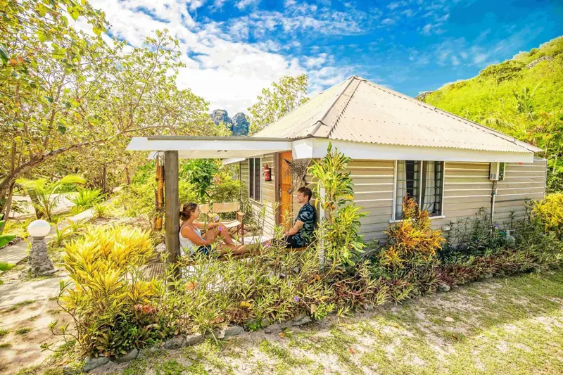 Une terrasse ombragée donne sur une petite maison de vacances.