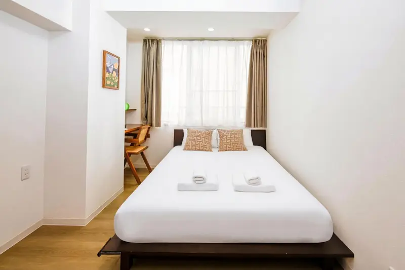 Une chambre lumineuse avec un lit double et une fenêtre.