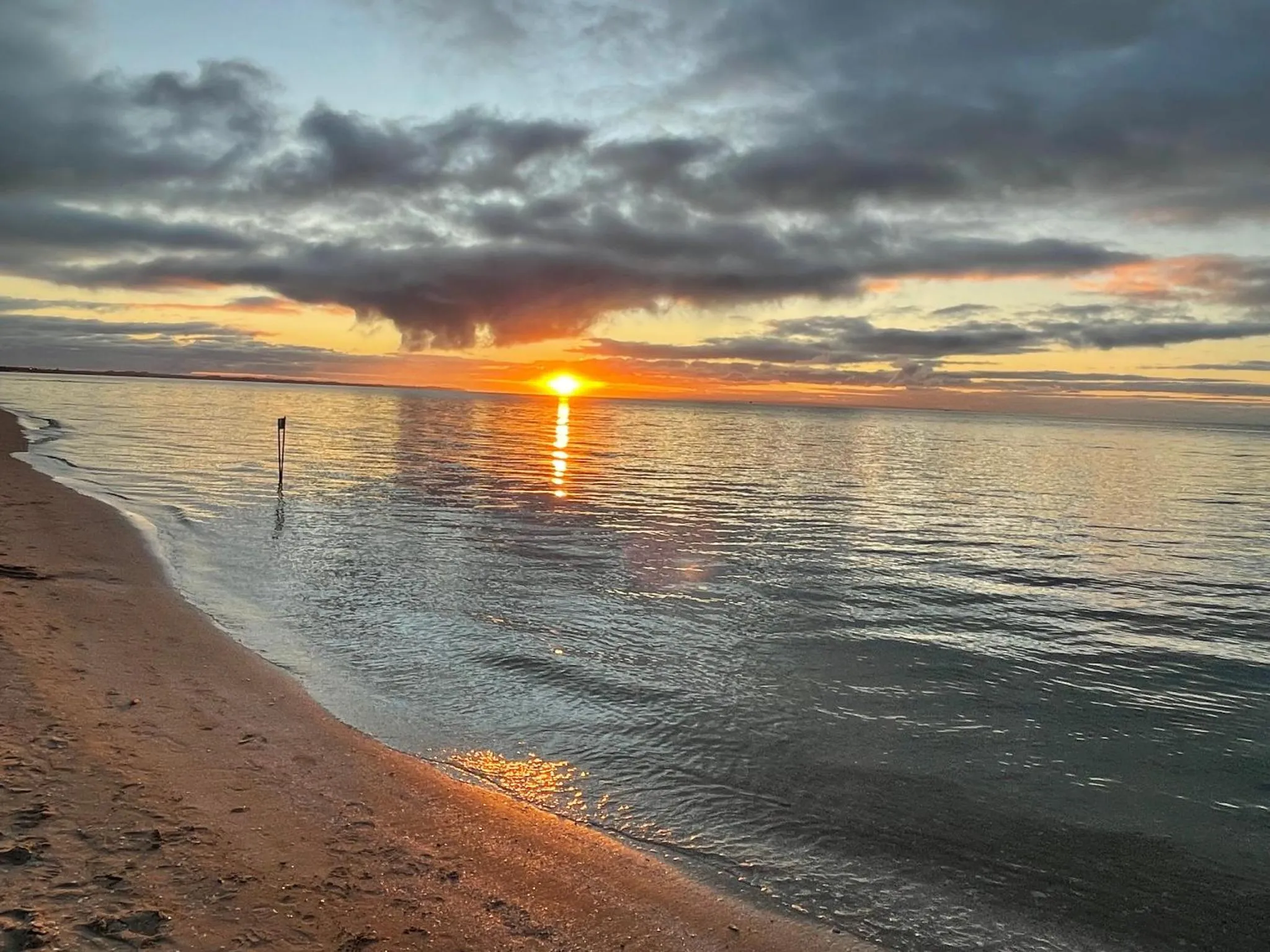 Coucher de soleil sur une plage de sable fin avec une mer calme.