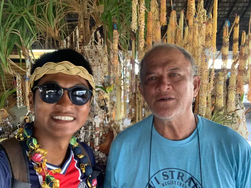 Deux personnes souriantes posent devant un décor végétal.