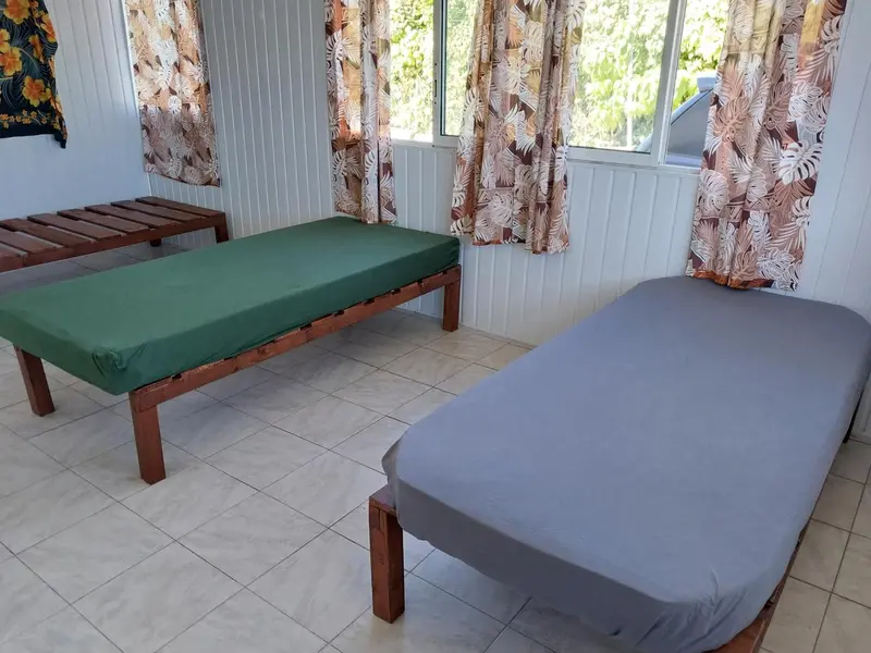 Une pièce lumineuse avec deux lits simples recouverts de draps.