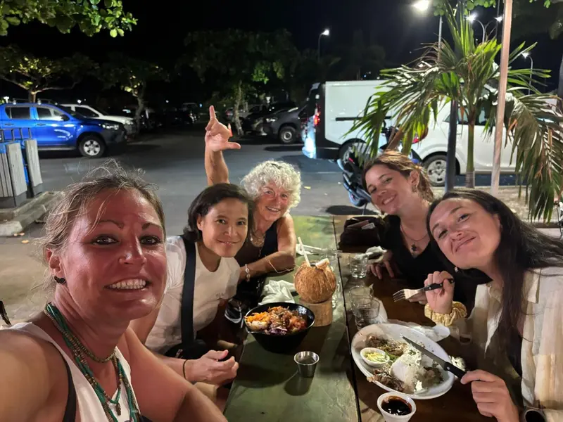 Un groupe de personnes souriantes est assises autour d'une table avec des plats.