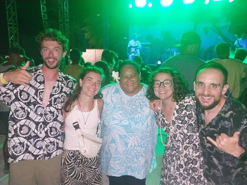 Un groupe de personnes souriantes pose devant une scène illuminée en vert.
