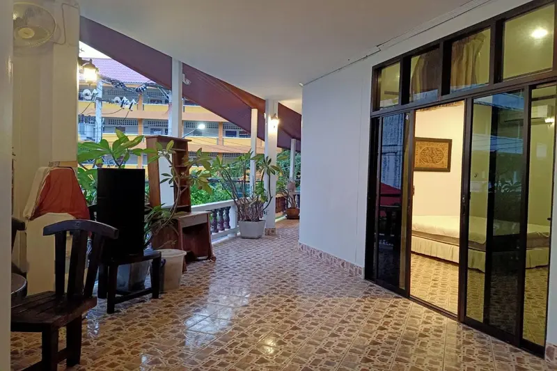 Terrasse carrelée avec mobilier et accès à une chambre.